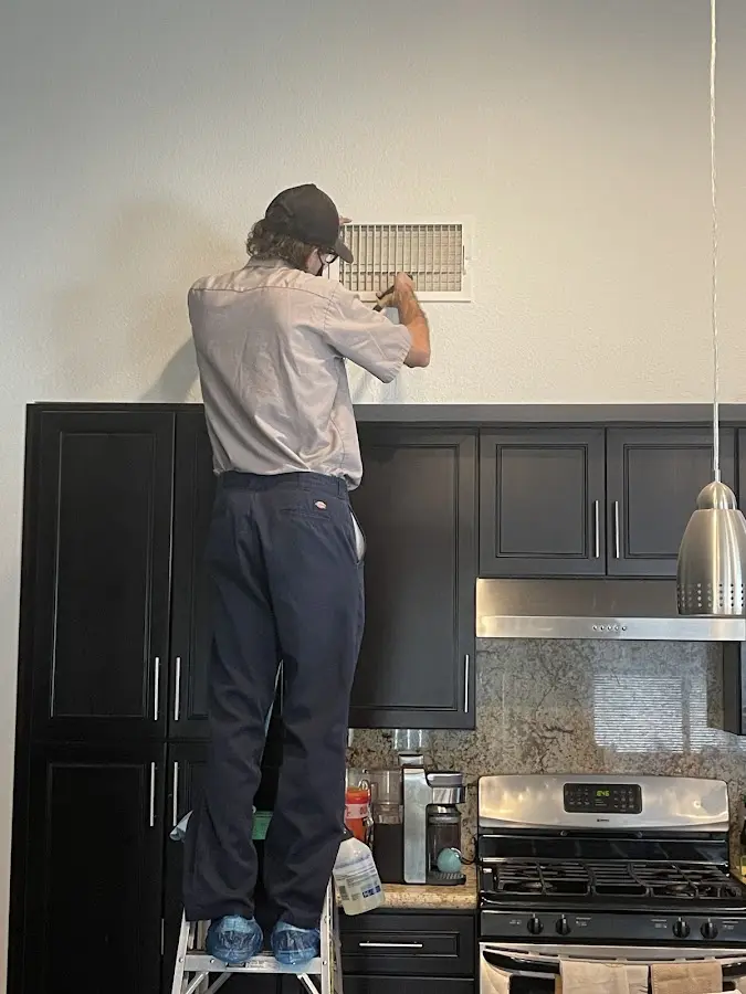 Technician inspecting an air vent during HVAC service in Trussville